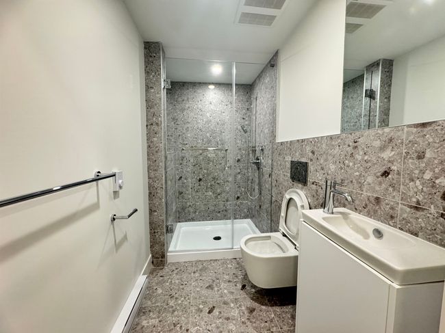 Bathroom with a stall shower, vanity, tile walls, toilet, and visible vents | Image 34