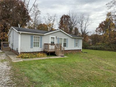 View of front facade featuring a wooden deck and a front lawn | Image 1