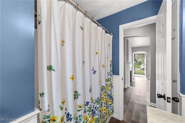 Full bathroom featuring a wainscoted wall, wood finished floors, and a shower with shower curtain | Image 17