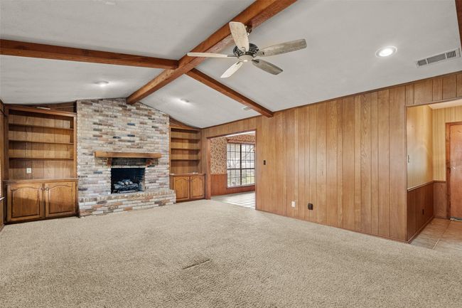 Unfurnished living room with carpet floors, wooden walls, and visible vents | Image 7