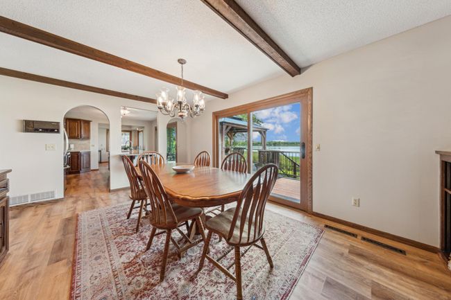 Formal dining room with wood beam ceiling, chandelier lighting, and sliding glass doors to the lakeside deck—perfect for dinner with a view. | Image 9