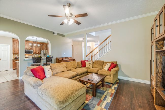 Living area featuring arched walkways, ceiling fan, wood finished floors, stairs, and ornamental molding | Image 13