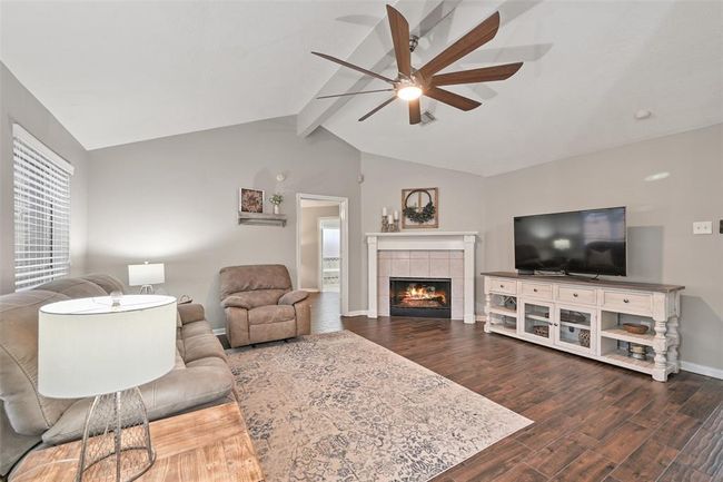 The inviting family room is anchored by large windows with backyard views and a cozy fireplace with decorative molding—blending warmth and style in this open-concept gathering space. | Image 9