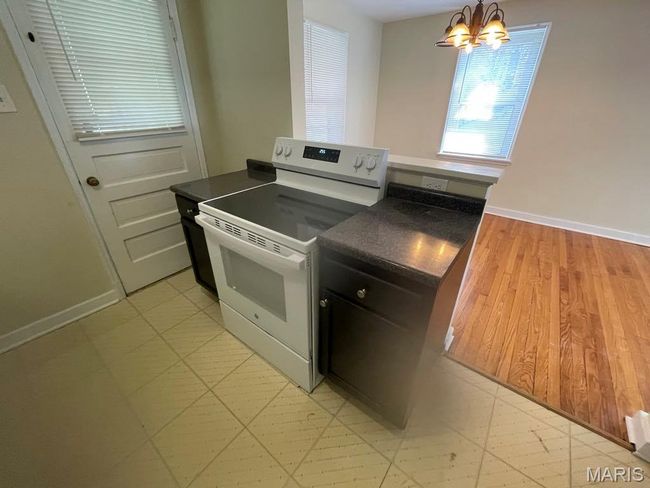 Kitchen featuring dark countertops, baseboards, a chandelier, and electric range | Image 8