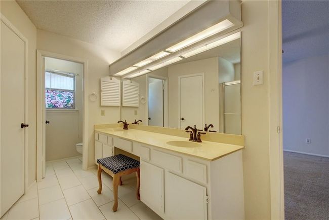 Bathroom featuring double vanity, a textured ceiling, a sink, and toilet | Image 19