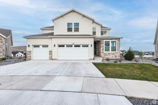 View of front facade with a front lawn, driveway, stone siding, and a garage | Image 5