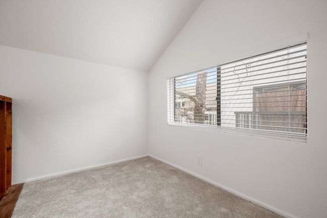 Carpeted empty room featuring baseboards and lofted ceiling | Image 10