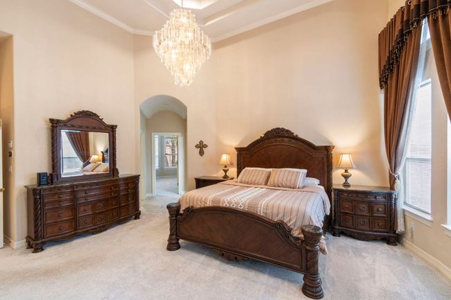 Bedroom featuring arched walkways, carpet, multiple windows, ornamental molding, and a high ceiling | Image 21