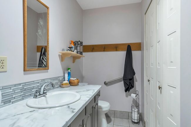 Bathroom with tile patterned flooring, toilet, vanity, and a closet | Image 19