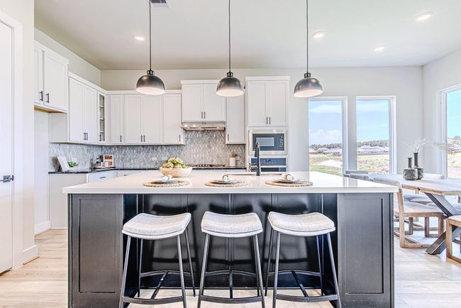 Gather in a chef’s kitchen that stuns with quartz countertops, white shaker cabinetry, and breathtaking views from the adjacent dining space. | Image 11