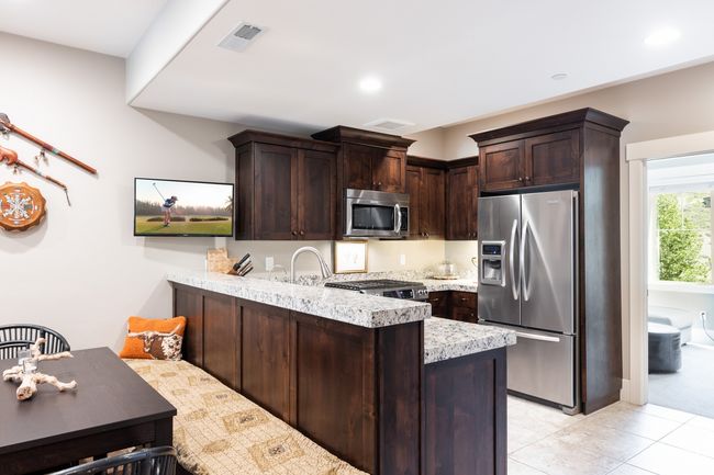 Kitchen with a peninsula, dark brown cabinetry, appliances with stainless steel finishes, and light tile patterned floors | Image 10