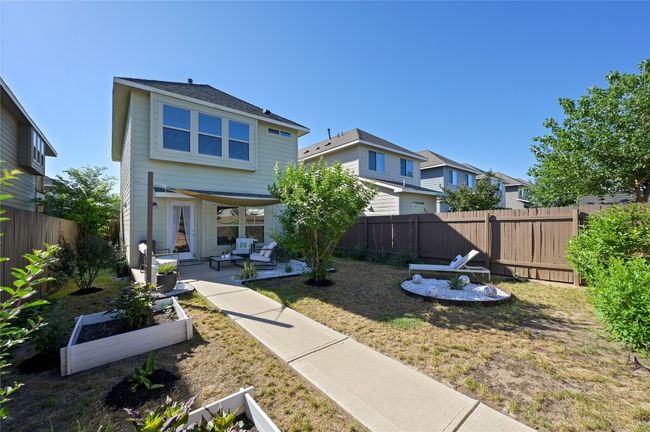 Rear view of house with a fenced backyard, an outdoor hangout area, a residential view, a patio area, and a lawn | Image 39