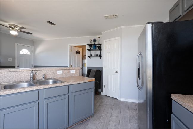 Kitchen featuring stainless steel fridge, a sink, a ceiling fan, light wood finished floors, and ornamental molding | Image 14
