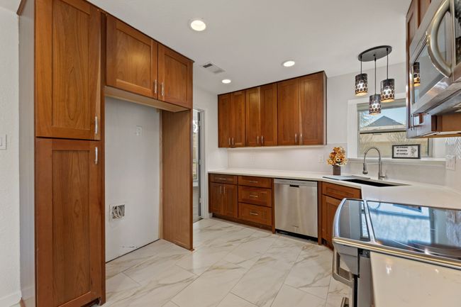 Kitchen with marble finish floor, a sink, visible vents, appliances with stainless steel finishes, and brown cabinets | Image 10