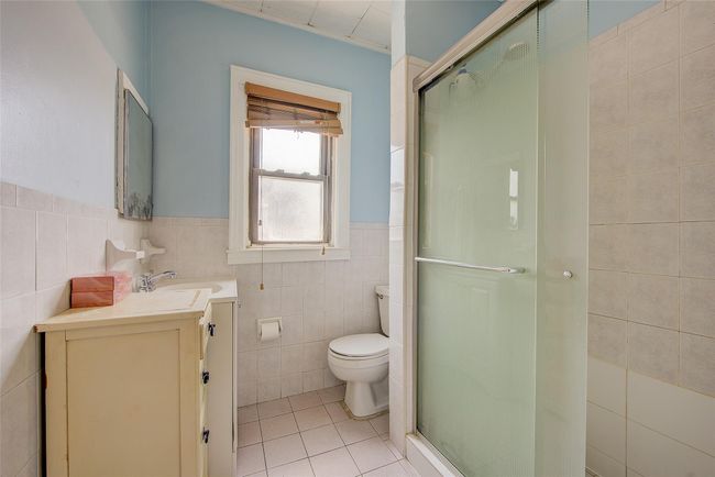 Bathroom with tile walls, tile patterned floors, vanity, a stall shower, and a wainscoted wall | Image 36