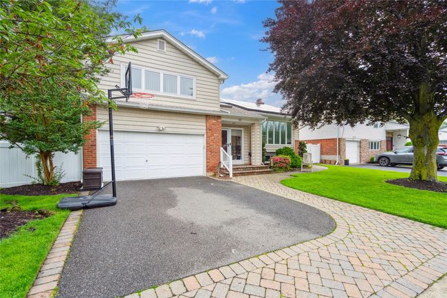 Split level home with driveway, an attached garage, a front lawn, and brick siding | Image 26