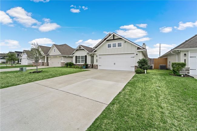View of front of home featuring board and batten siding, a front yard, concrete driveway, and central air condition unit | Image 33