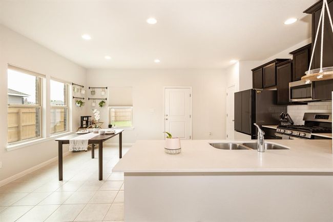 Kitchen featuring stainless steel appliances, dark brown cabinetry, light countertops, recessed lighting, and tasteful backsplash | Image 13