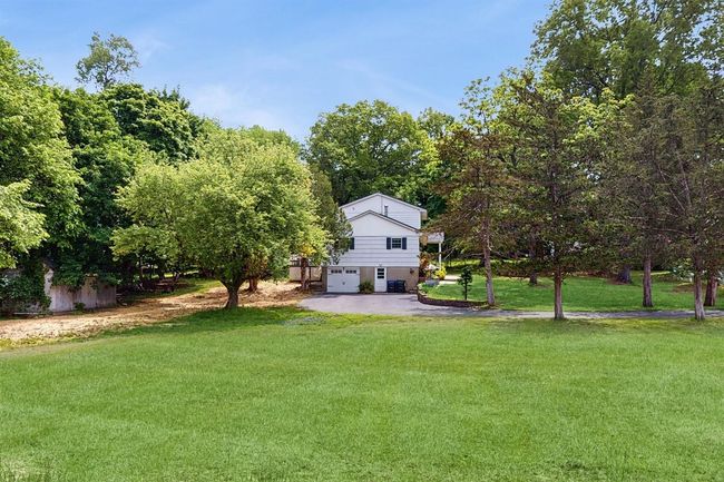 View of beatiful green lawn featuring a very long driveway and a 1 car garage. | Image 35