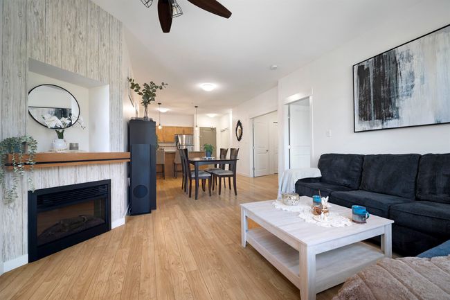 Living area with ceiling fan, a glass covered fireplace, and light wood-type flooring | Image 4