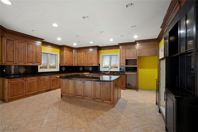 Kitchen with dark countertops, ornamental molding, backsplash, light tile patterned flooring, and a center island | Image 18