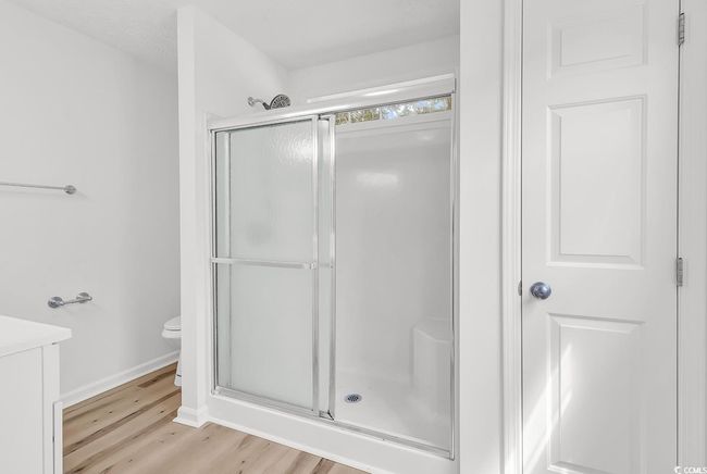 Bathroom featuring vanity, wood finished floors, toilet, baseboards, and a shower stall | Image 12