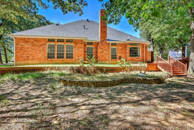Rear view of house with a patio area, a shingled roof, a chimney, and brick siding | Image 35