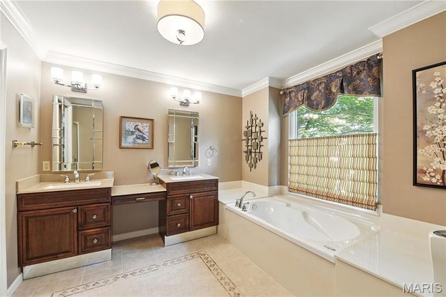 Full bath with tile patterned flooring, a bath, two vanities, ornamental molding, and inlaid floor details | Image 11