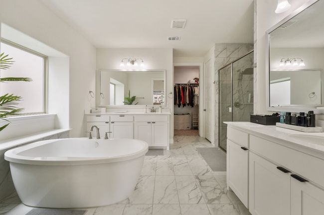 Full bath with marble finish flooring, a shower stall, two vanities, a freestanding bath, and a walk in closet | Image 12