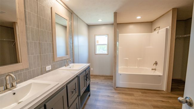 Bathroom featuring wood finished floors, double vanity, decorative backsplash, shower combination, and recessed lighting | Image 31