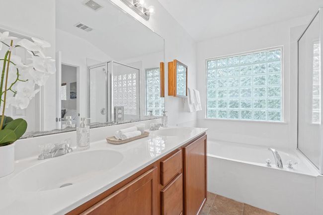 Full bathroom featuring a bath, double vanity, a shower stall, and vaulted ceiling | Image 19