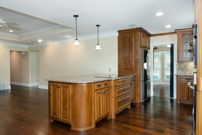 Kitchen featuring stainless steel fridge, crown molding, dark wood finished floors, backsplash, and ceiling fan | Image 15