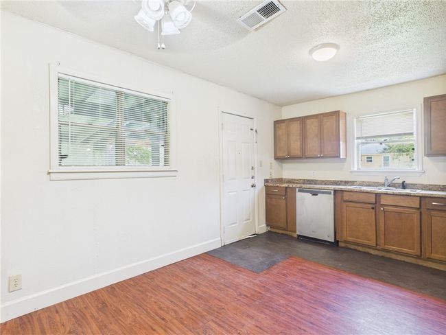 Kitchen with dishwasher, brown cabinets, a ceiling fan, dark wood-type flooring, and a textured ceiling | Image 4