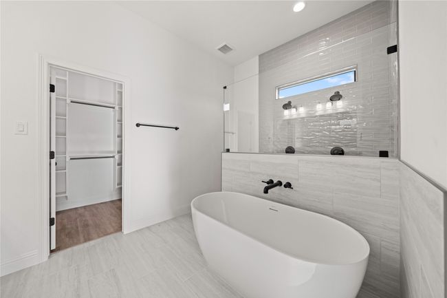 Bathroom featuring a soaking tub, a walk in closet, baseboards, and a tile shower | Image 21
