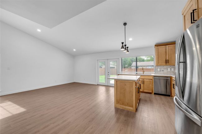 Kitchen with stainless steel appliances, light countertops, light wood-type flooring, a kitchen island, and tasteful backsplash | Image 15