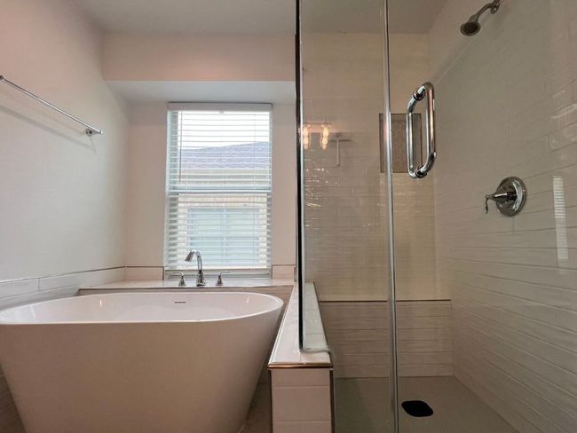 Bathroom with a stall shower, a freestanding bath, a wainscoted wall, and tile walls | Image 20