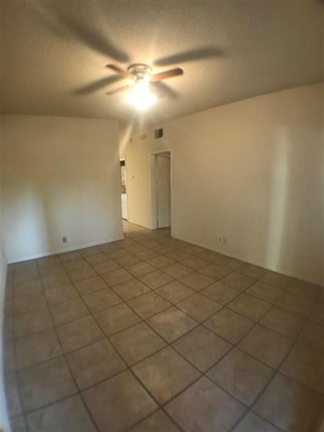 Spare room featuring light tile patterned flooring, a textured ceiling, ceiling fan, and visible vents | Image 5