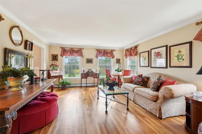 Living area featuring baseboard heating, crown molding, and wood finished floors | Image 6
