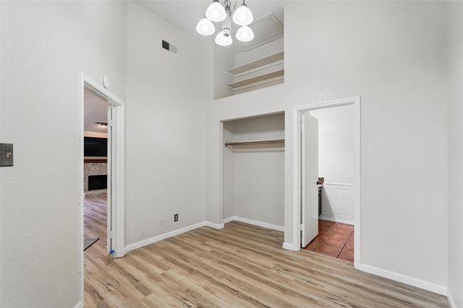 Unfurnished bedroom with LVT, a chandelier, a high ceiling, baseboards, and a closet | Image 15