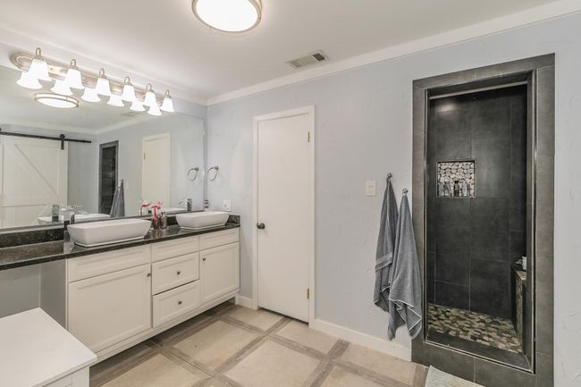 Bathroom featuring double vanity, crown molding, and a tile shower | Image 19