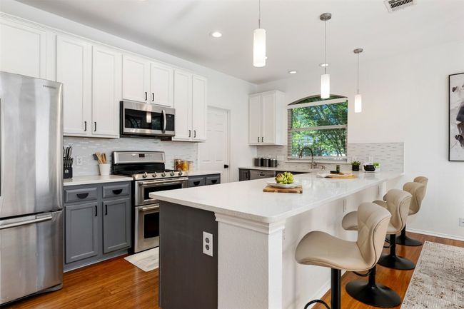 Kitchen with gray cabinetry, light countertops, wood finished floors, and appliances with stainless steel finishes | Image 9