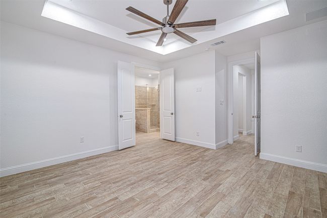 Unfurnished bedroom featuring light wood-type flooring, a raised ceiling, and baseboards | Image 23