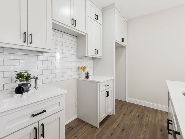 Kitchen featuring dark wood finished floors, baseboards, tasteful backsplash, and white cabinets | Image 10