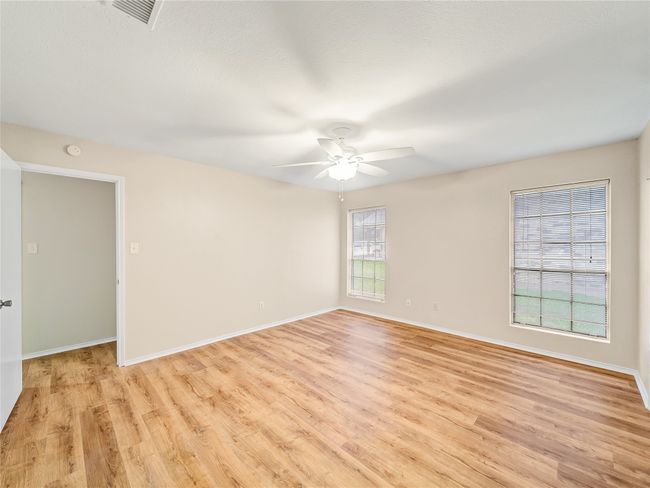 Empty room featuring light wood finished floors, a ceiling fan, baseboards, and a smoke detector | Image 12