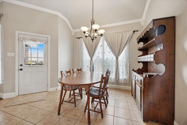 Dining area featuring a chandelier, crown molding, light tile patterned floors, and baseboards | Image 9