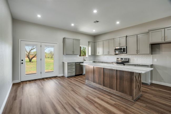 Kitchen with tasteful backsplash, visible vents, gray cabinetry, dark wood-type flooring, and appliances with stainless steel finishes | Image 6