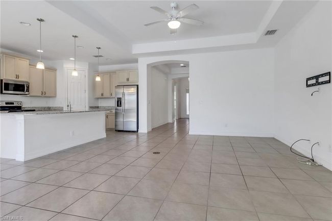 Kitchen featuring stainless steel appliances, arched walkways, cream cabinetry, ceiling fan, and light tile patterned floors | Image 20