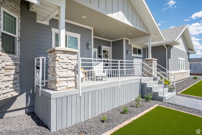 View of exterior entry with stone siding, covered porch, a shingled roof, and board and batten siding | Image 9