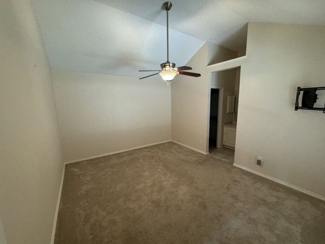 Master bedroom with ceiling fan, light tile floors, a textured ceiling, ensuite bath, and lofted ceiling | Image 14