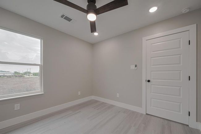 This restful bedroom features a large window, soft neutral tones, ceiling fan, and recessed lighting—providing a comfortable and peaceful atmosphere. | Image 26
